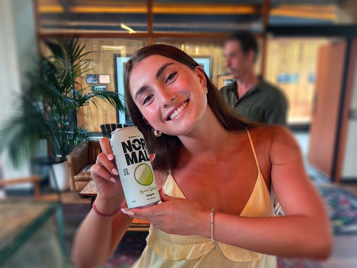 A young female holds a Normal Beverage Agave Splash Margarita can